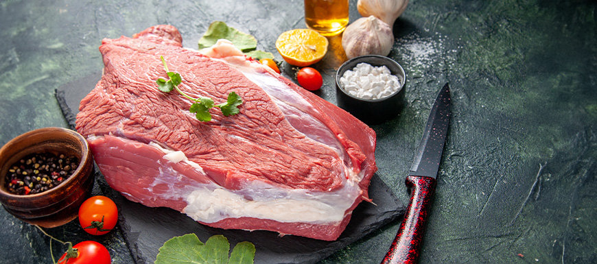 Raw steak on a black slate with toppings